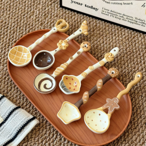 Cute ceramic spoons with food-inspired designs arranged on a wooden serving tray