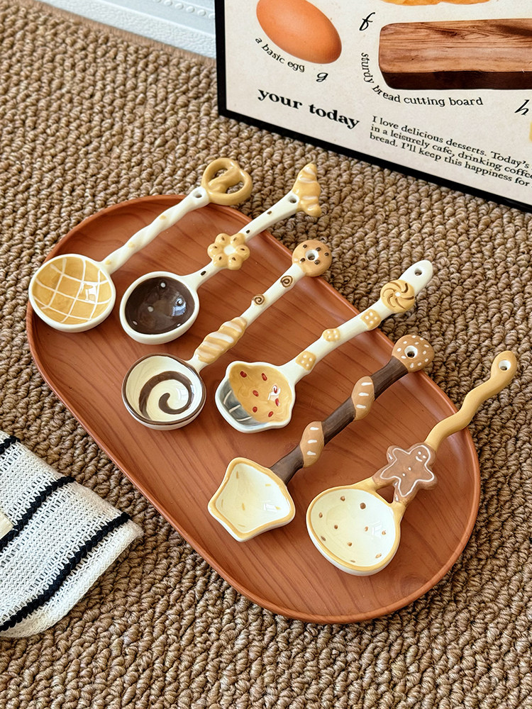 Cute ceramic spoons with food-inspired designs arranged on a wooden serving tray