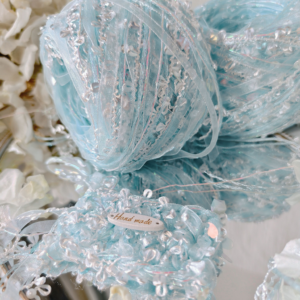 Iridescent blue textured art yarn ball with shimmering fibers and decorative details