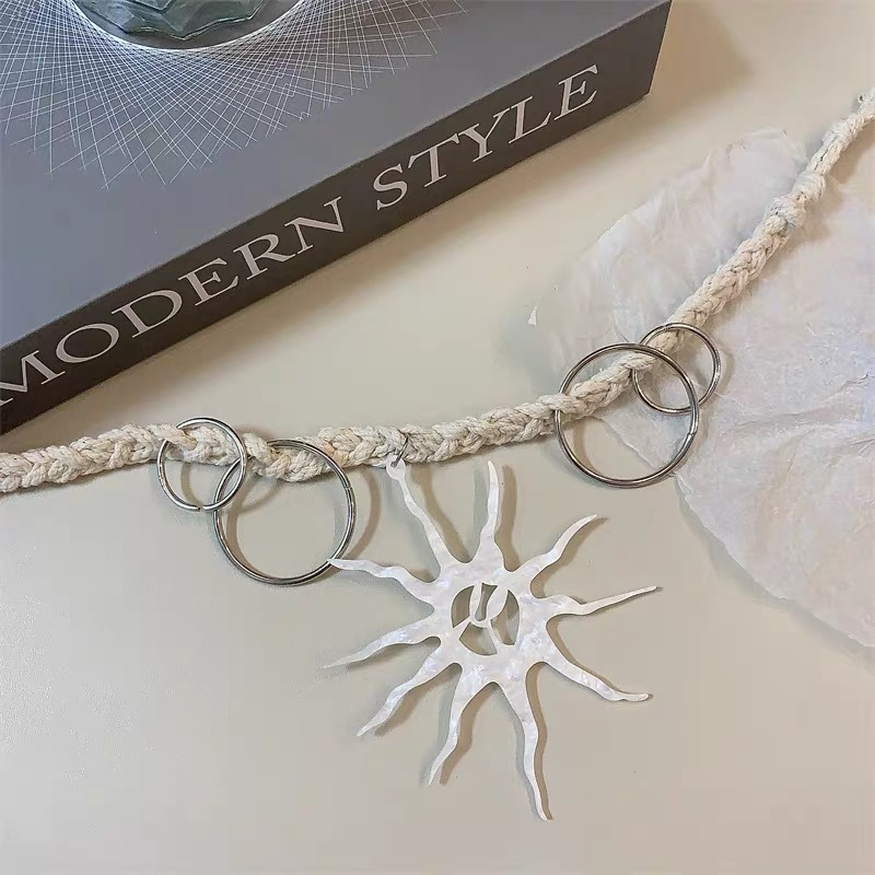 Celestial-inspired sun necklace showing the textured pendant, cord and circular metal accents